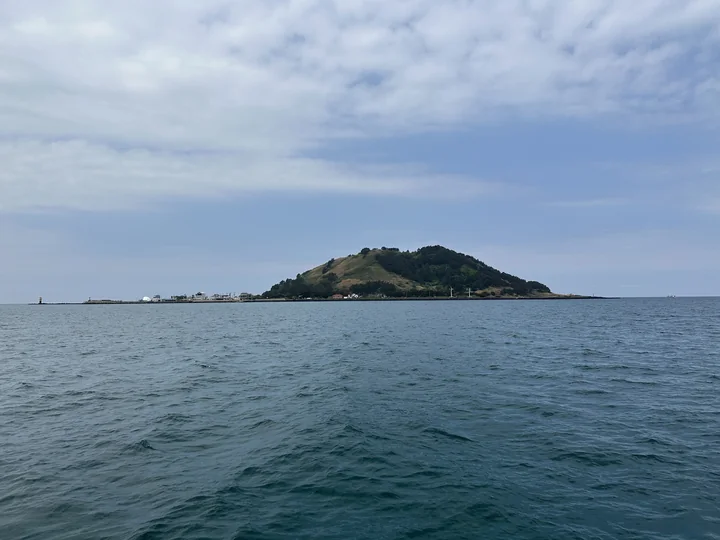The green volcanic cone of Biyangdo rises above the sea off Hallim on the western coast of Jeju.