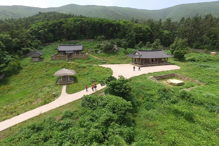 Traditional Korean buildings sit below a wooded mountain at Nakseojae on Bogildo.