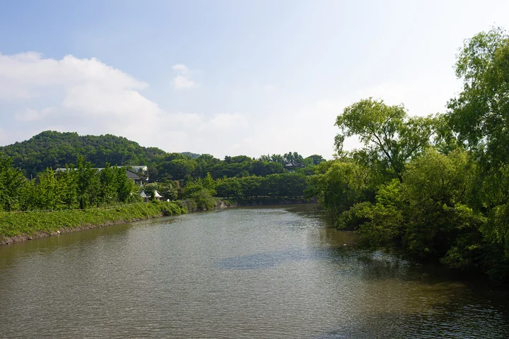 Calm water bordered by green trees and low hills on Ganghwa Island.
