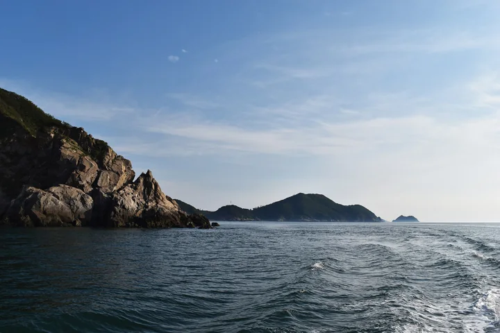 Rocky cliffs and green hills rise from the sea beside Gauido in Taeanhaean National Park.