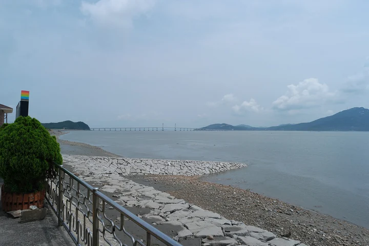 The seawall and shoreline at Wolseonpo on Gyodongdo, with Gyodong Bridge in the distance.