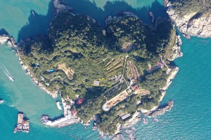 An aerial view of terraced gardens and wooded paths on Oedo, surrounded by turquoise water.