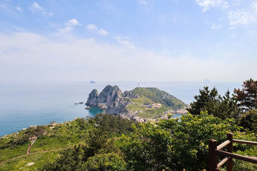 Green slopes and rocky cliffs surround the lighthouse islet viewed from Somaemuldo.