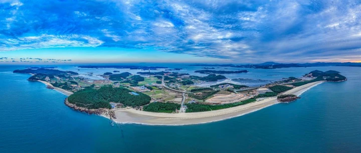 An aerial view of Wonsando shows forested hills, villages and pale beaches curving along the coast.