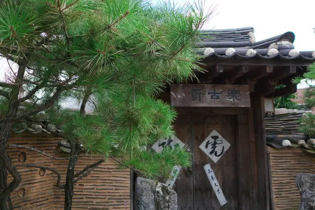The tiled entrance gate of Rakkojae Seoul beneath a pine tree